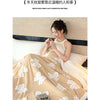 A woman is relaxing in bed under a thick beige jacquard lambswool blanket with white floral patterns.