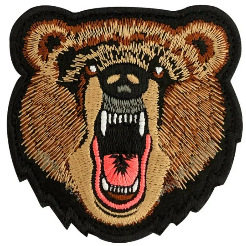 An embroidered patch depicting a fierce brown bear face with open jaws and white teeth.