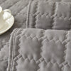A close-up of a gray quilted anti-slip sofa cover with a plush texture lying on a surface.