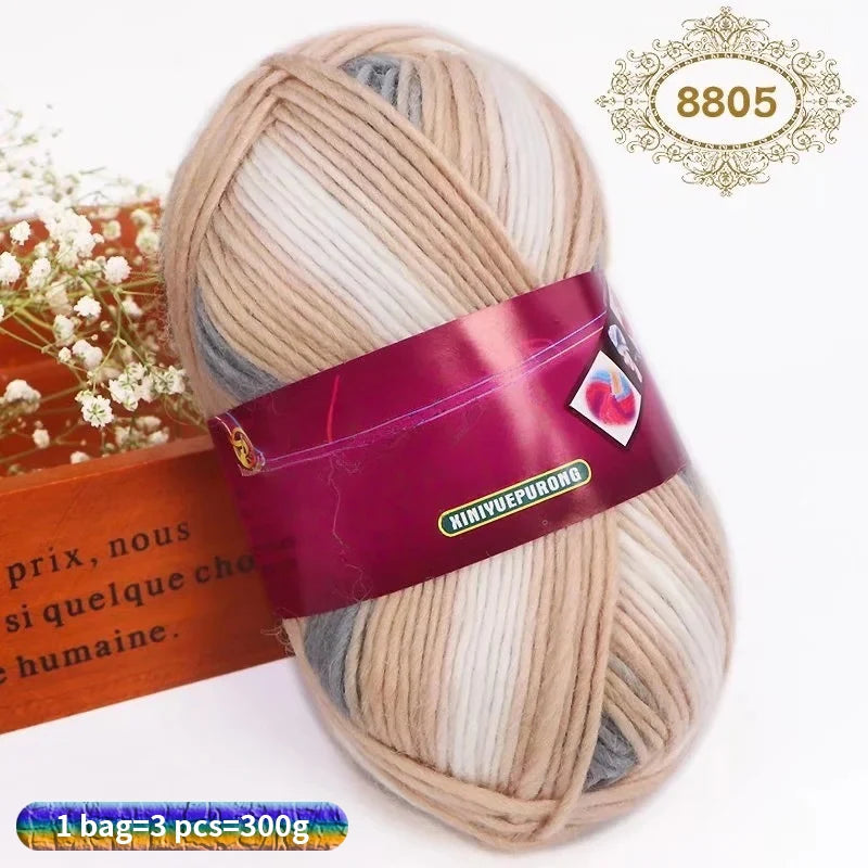 A ball of gradient dyed wool yarn in beige and gray colors with a pink label and a gold stamp.
