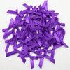 A pile of small purple satin ribbon bows for crafts and decor.