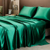 A luxury solid emerald green satin bedding set draped on a bed with neutral tones.