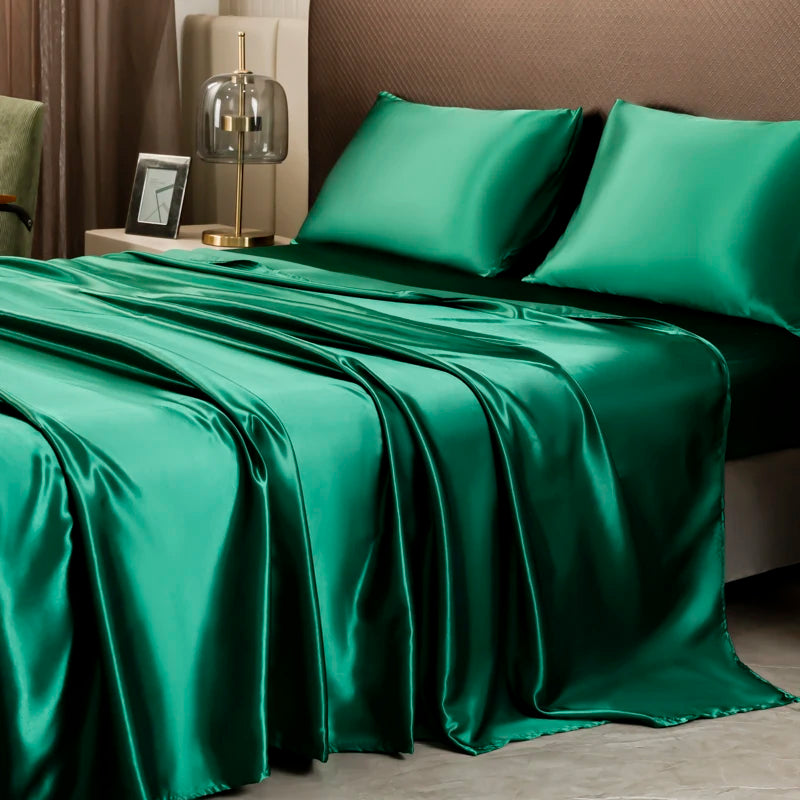 A luxury solid emerald green satin bedding set draped on a bed with neutral tones.