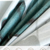 Close-up of a teal grey microfiber fabric showing watercolor floral patterns and texture.