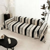 A bohemian striped sofa cover featuring black and white vertical stripes on a light-colored sofa.