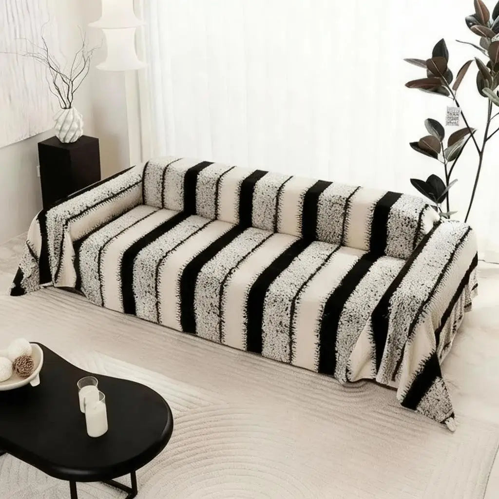 A bohemian striped sofa cover featuring black and white vertical stripes on a light-colored sofa.