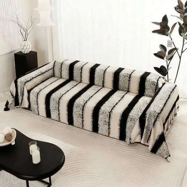 A bohemian striped sofa cover featuring black and white vertical stripes on a light-colored sofa.