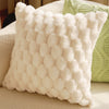 A white, textured plush pillow cover with a dimpled pattern resting on a light-colored surface.