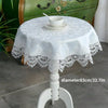 White embroidered lace tablecloth with an elegant edge set on a white pedestal table.