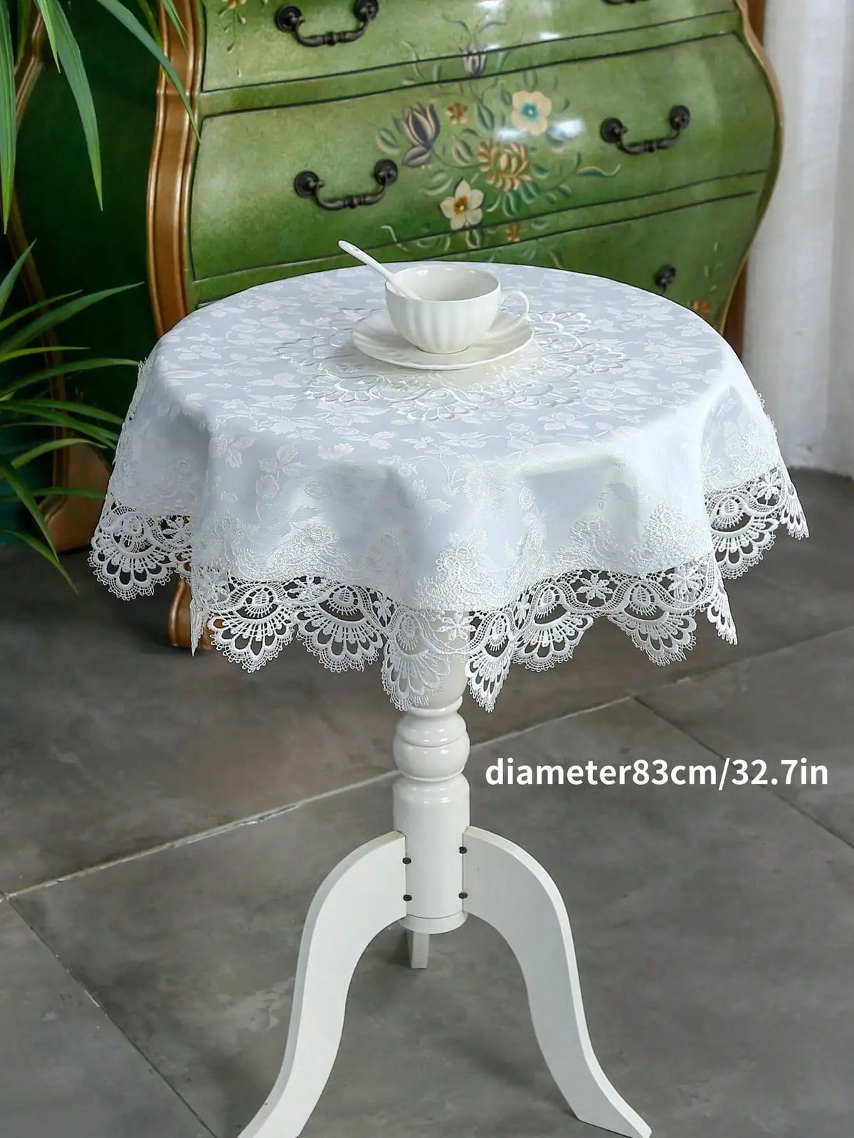 White embroidered lace tablecloth with an elegant edge set on a white pedestal table.