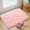 A fluffy pink bedroom carpet with a non-slip backing is displayed on a wooden floor.