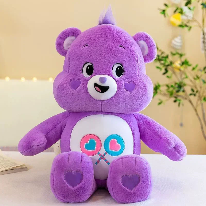 A purple Care Bears Rainbow Bear plush toy with pink accents sitting on a white surface.