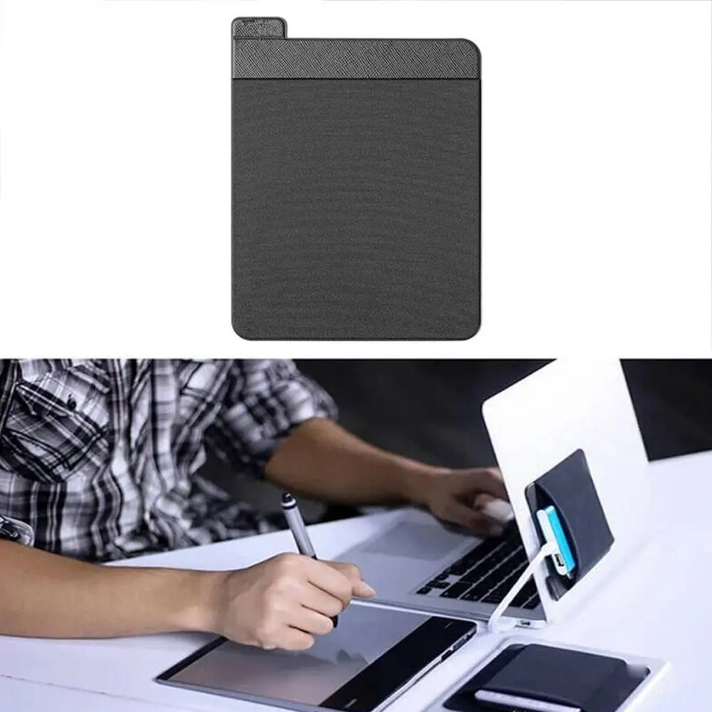 A dark gray adhesive laptop back storage pouch is shown next to a laptop.