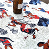 A close-up of bohemian printed linen fabric featuring colorful tribal figures and patterns on a white background.