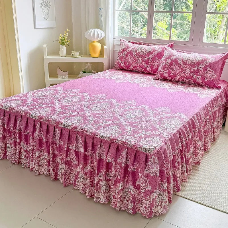 A pink floral print bed skirt set covering a bed with white and light purple accents.