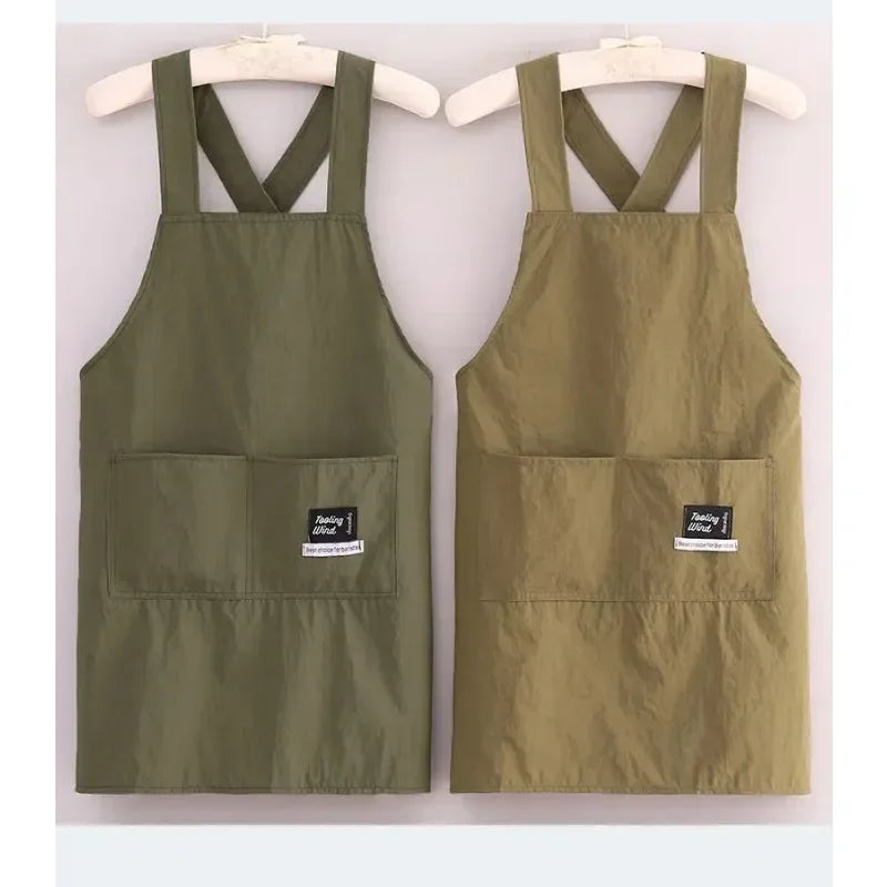 A pair of olive green water-resistant kitchen aprons hanging on a wooden hanger.