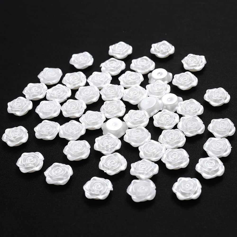 A scattering of small, white imitation pearl flower spacer beads on a black background.