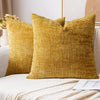 A close-up of a golden yellow boucle texture throw pillow cover resting on a white sofa.
