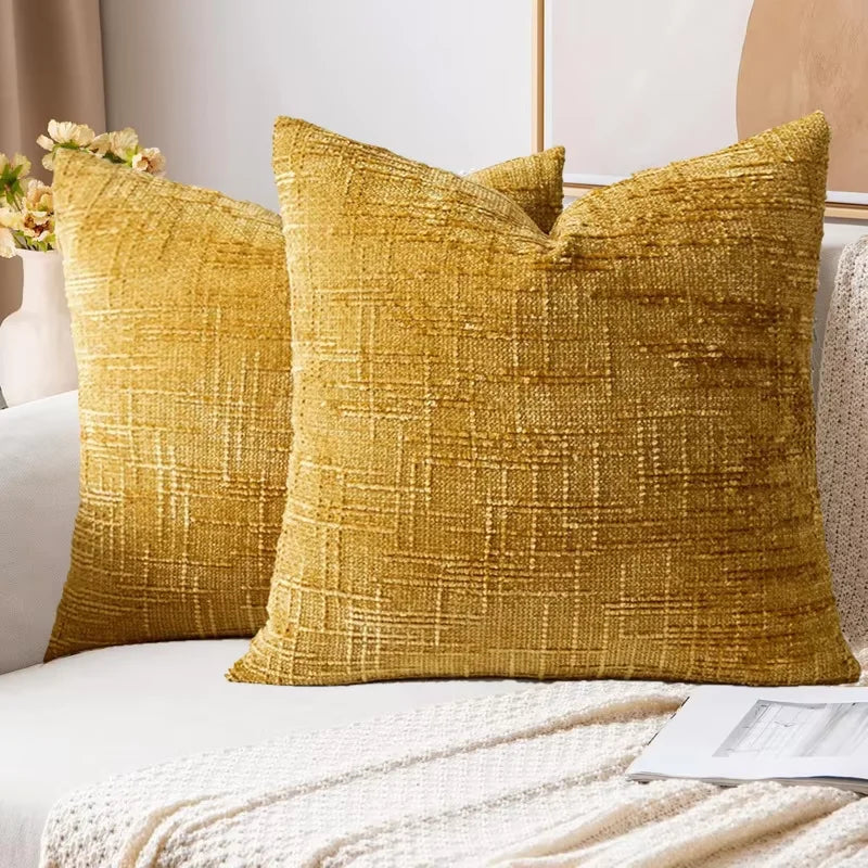 A close-up of a golden yellow boucle texture throw pillow cover resting on a white sofa.