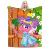 A colorful cartoon illustration of Elmo and friends on a flannel throw blanket.