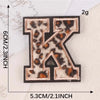 A black iron-on patch shaped like the letter K with a leopard print design.
