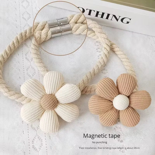 A set of two beige braided rope tiebacks with floral accents used for curtain ties.