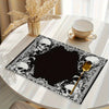 A black placemat featuring a vintage gothic floral design with skulls and mystic cross elements on a white table.