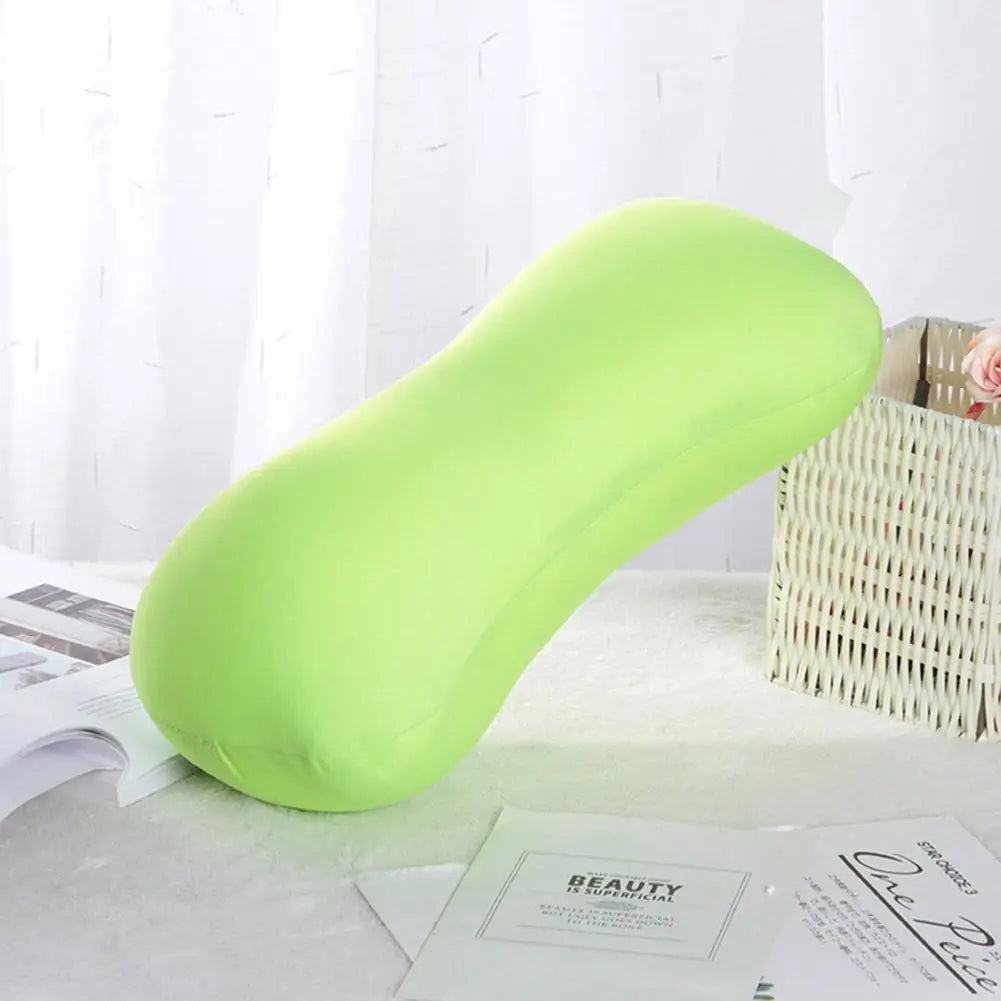 A bright lime green microbead neck pillow resting on a white surface next to a woven basket.