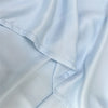 Light blue luxury bamboo flat sheets draped softly, showing fabric texture and folds.