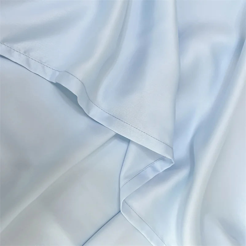 Light blue luxury bamboo flat sheets draped softly, showing fabric texture and folds.