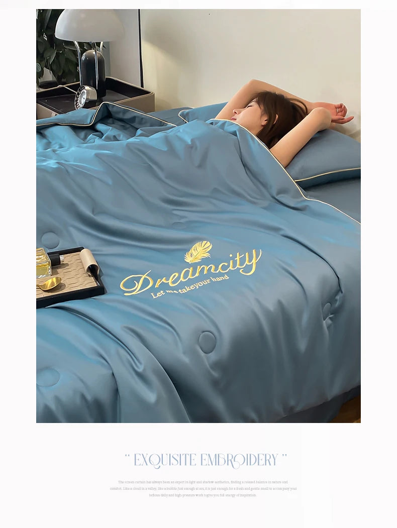 A person is relaxing under a blue quilt with gold embroidery on it.