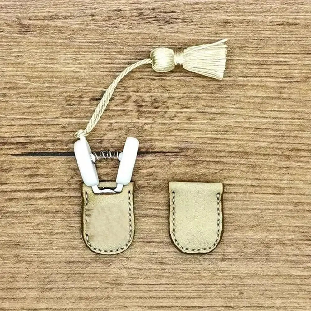 Mini precision sewing scissors with a protective cover and a gold-colored fabric tie on a wooden background.