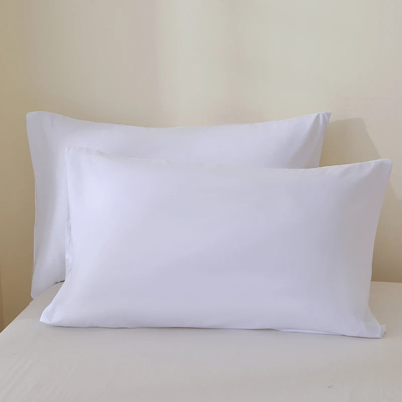 A set of three white luxury brushed fabric pillowcases stacked on a white surface.