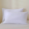 A set of three white luxury polyester pillow covers resting on a white surface.