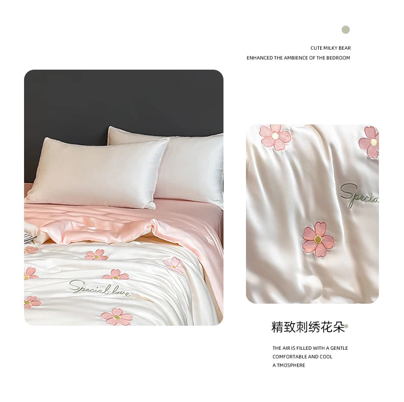 A close-up of a light pink embroidered quilt with floral patterns, featuring a soft, breathable fabric.
