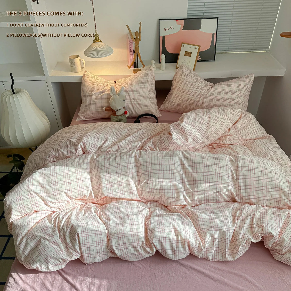 A pink plaid duvet cover set with matching pillowcases displayed on a bed, next to decorative items.