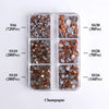 A clear plastic tray containing various sizes of gold and silver glass rhinestones for crafting.
