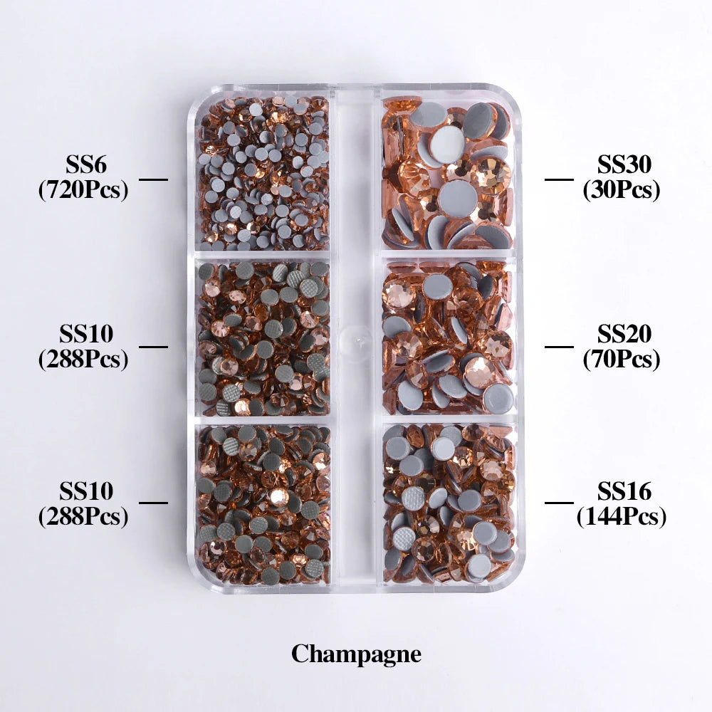 A clear plastic tray containing various sizes of gold and silver glass rhinestones for crafting.