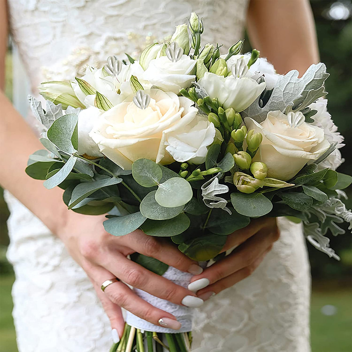 A bride holds a bouquet of white roses and greenery for crafting.