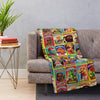 A colorful blanket featuring various sheep and related themes draped over a gray sofa.