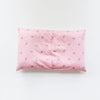 A pink soft cotton baby pillow cover with a repeating pattern of small crowns.