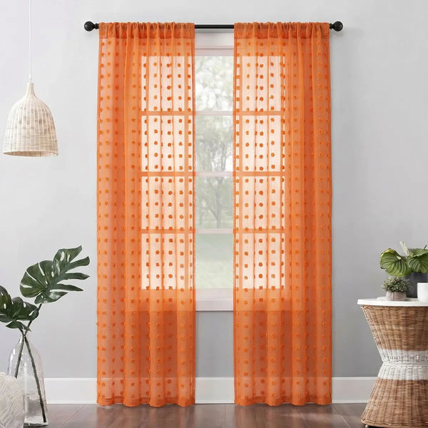 Orange pompom jacquard sheer curtain hanging in a window frame