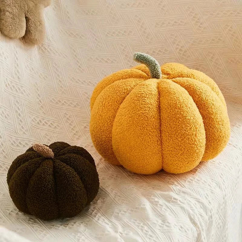 A bright orange fuzzy pumpkin shaped throw pillow resting on a white textured fabric.
