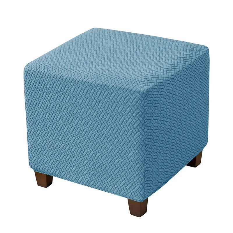 A square blue jacquard stretch ottoman slipcover with a diamond pattern.