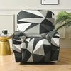 A modern armchair upholstered in a geometric black and white pattern sits on a wooden floor.