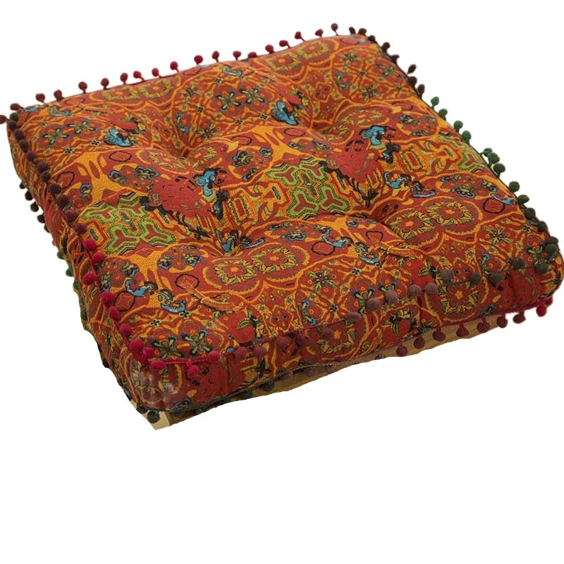 An orange and red bohemian cotton linen throw cushion with decorative fringe.