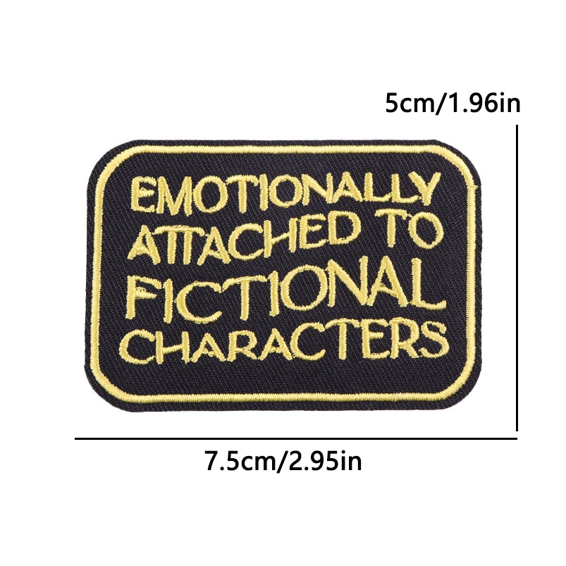 Black iron-on embroidery patch with yellow text that reads Emotionally Attached to Fictional Characters