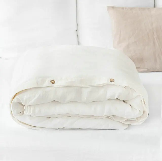 White luxury French linen duvet cover folded on a white surface.