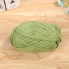 A ball of light green flat thread yarn for crafting and sewing resting on a wooden surface.
