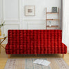 A deep red velvet armless sofa cover displayed against a white wall with framed art and wooden shelving.